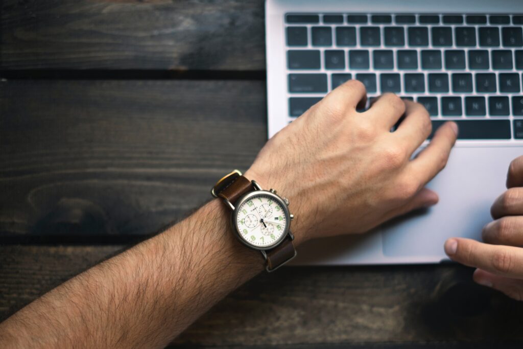 arm of a man placed on a computer wearing brown watch 
